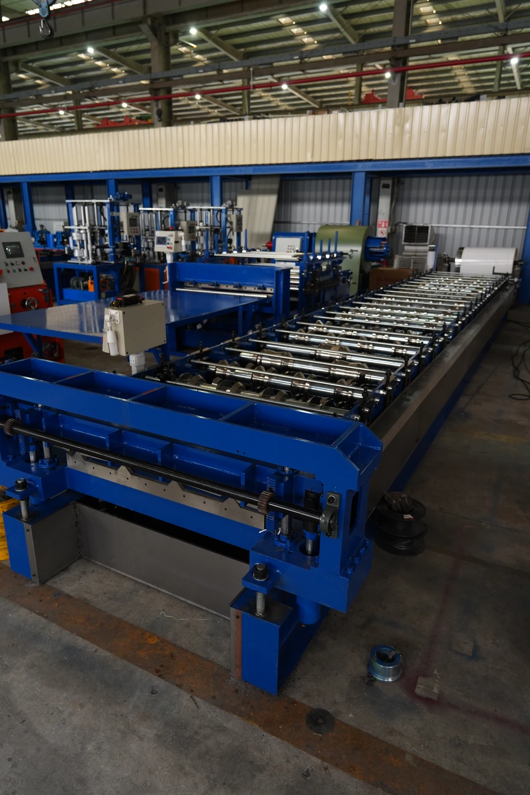 Linha de perfilagem com rolos, estruturas e painel de comando numa oficina de fabricação