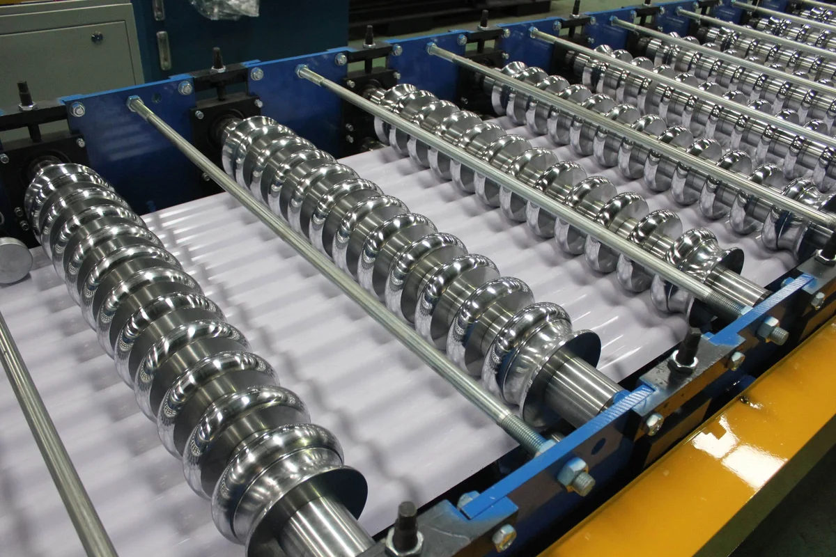 Polished forming rolls shaping a white corrugated roof sheet