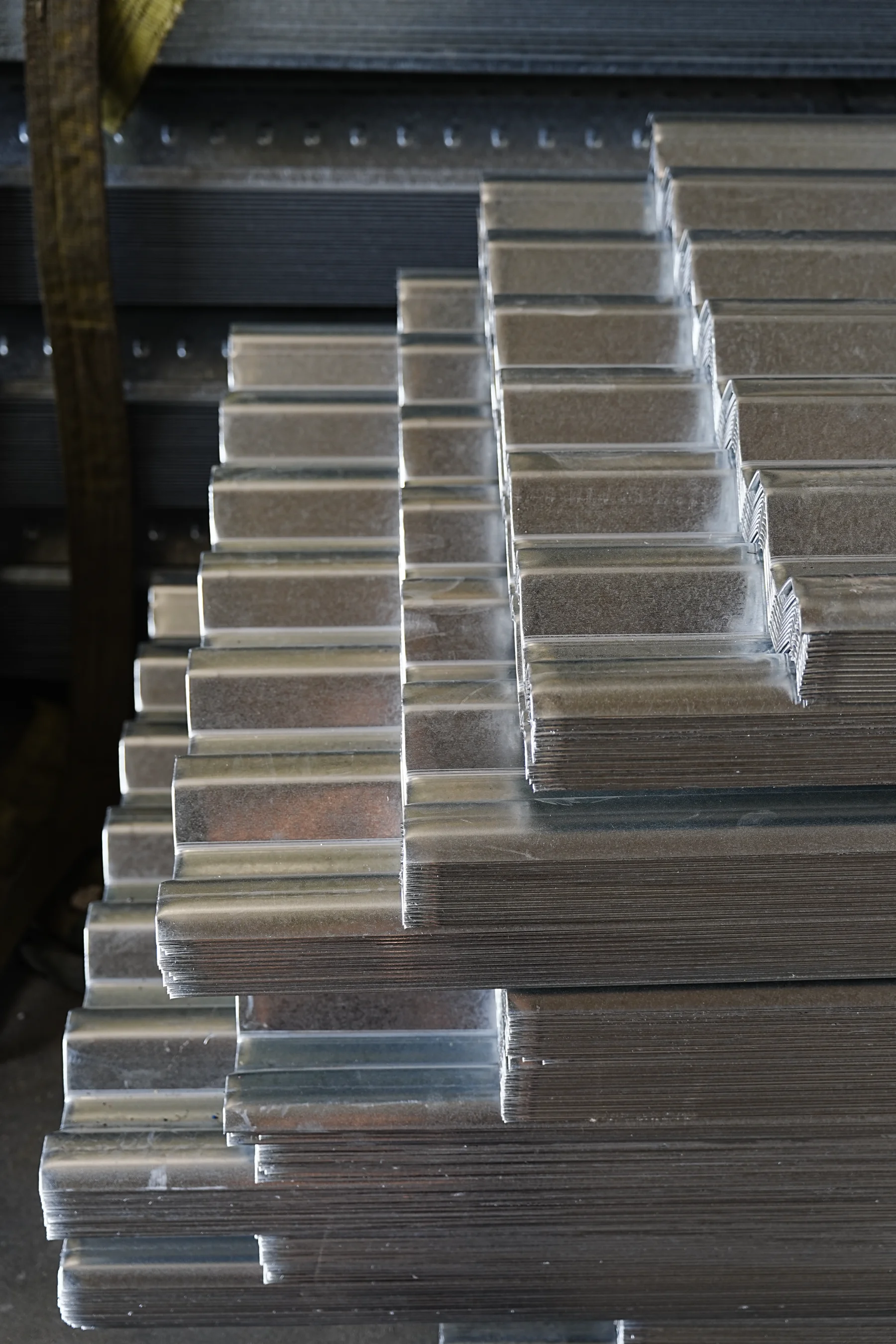 Stacks of galvanized roll-formed metal sections photographed during a production-base workshop site visit